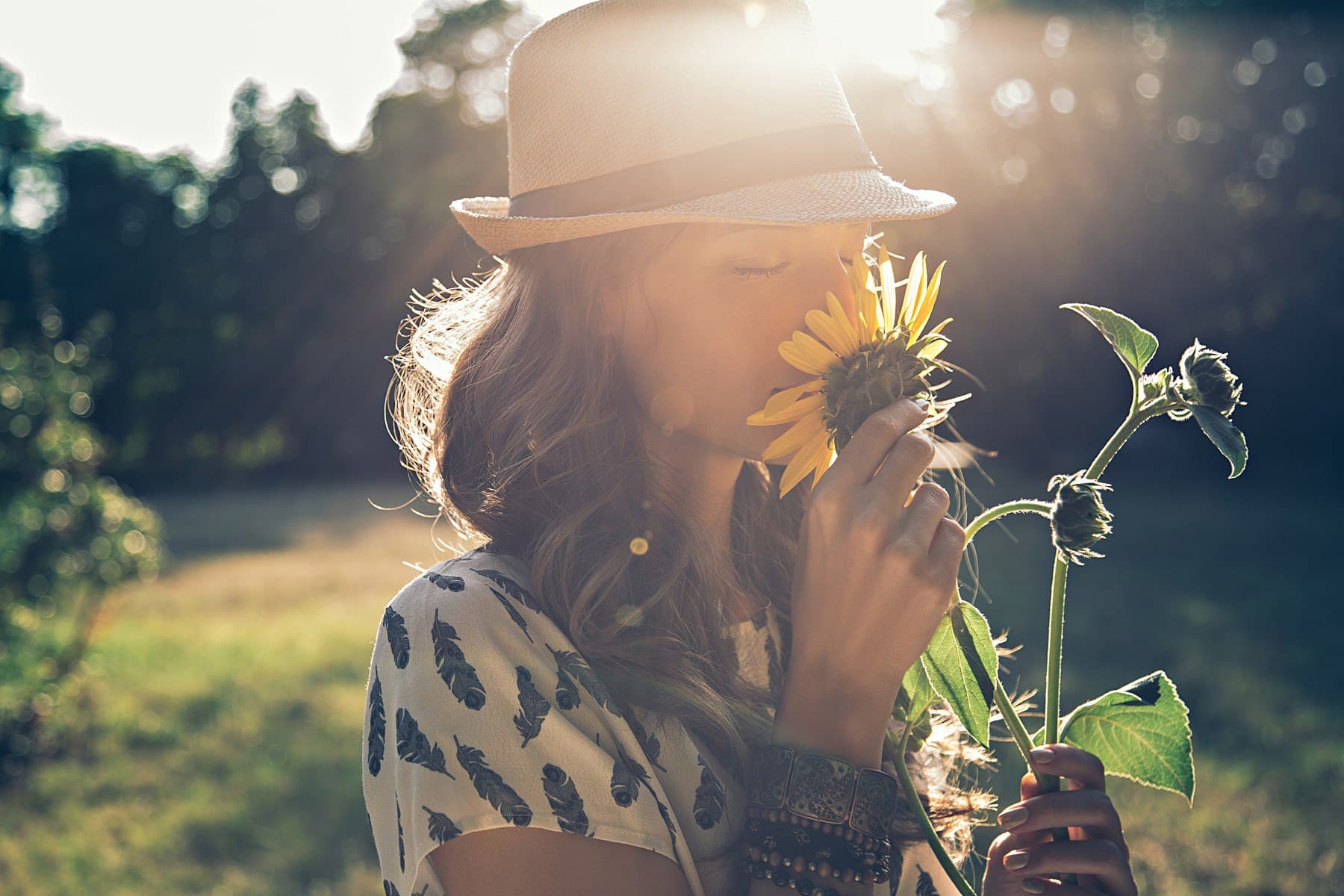 young woman outside smelling a wildflower