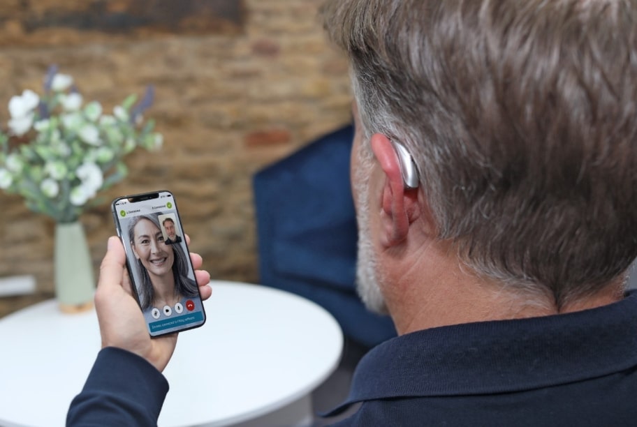 A man video chats a woman through Phonak hearing device.