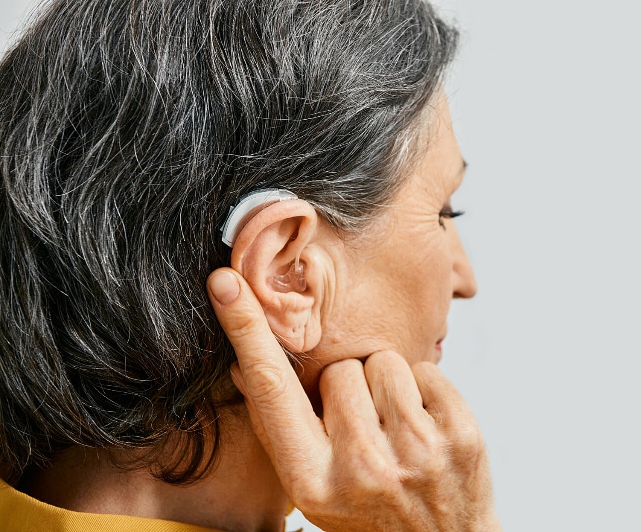 A woman fitted with a prescription hearing aid, highlighting the importance of assistive devices for individuals with hearing loss.
