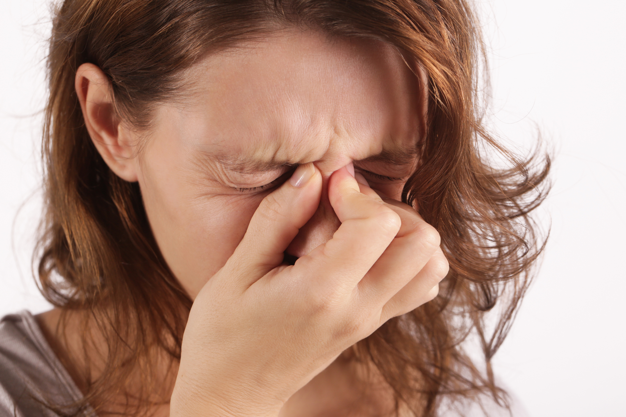 A woman rubbing her eyes with her hands, showing signs of discomfort from chronic rhinosinusitis.